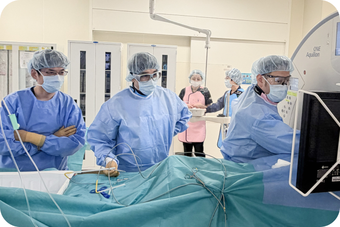 手術着とマスクを着けた医療スタッフが、処置中の患者を囲んで作業する医療現場