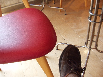 [a red chair and a dirty shoe in a cafe]
